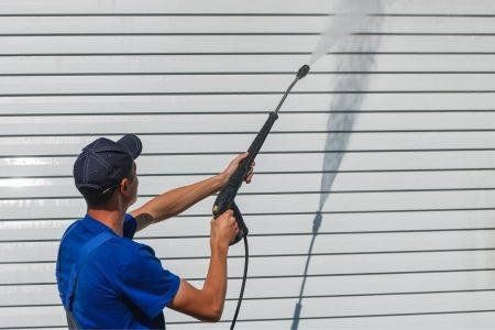 worker-overalls-washes-white-wall-from-siding-with-water-gun.jpg